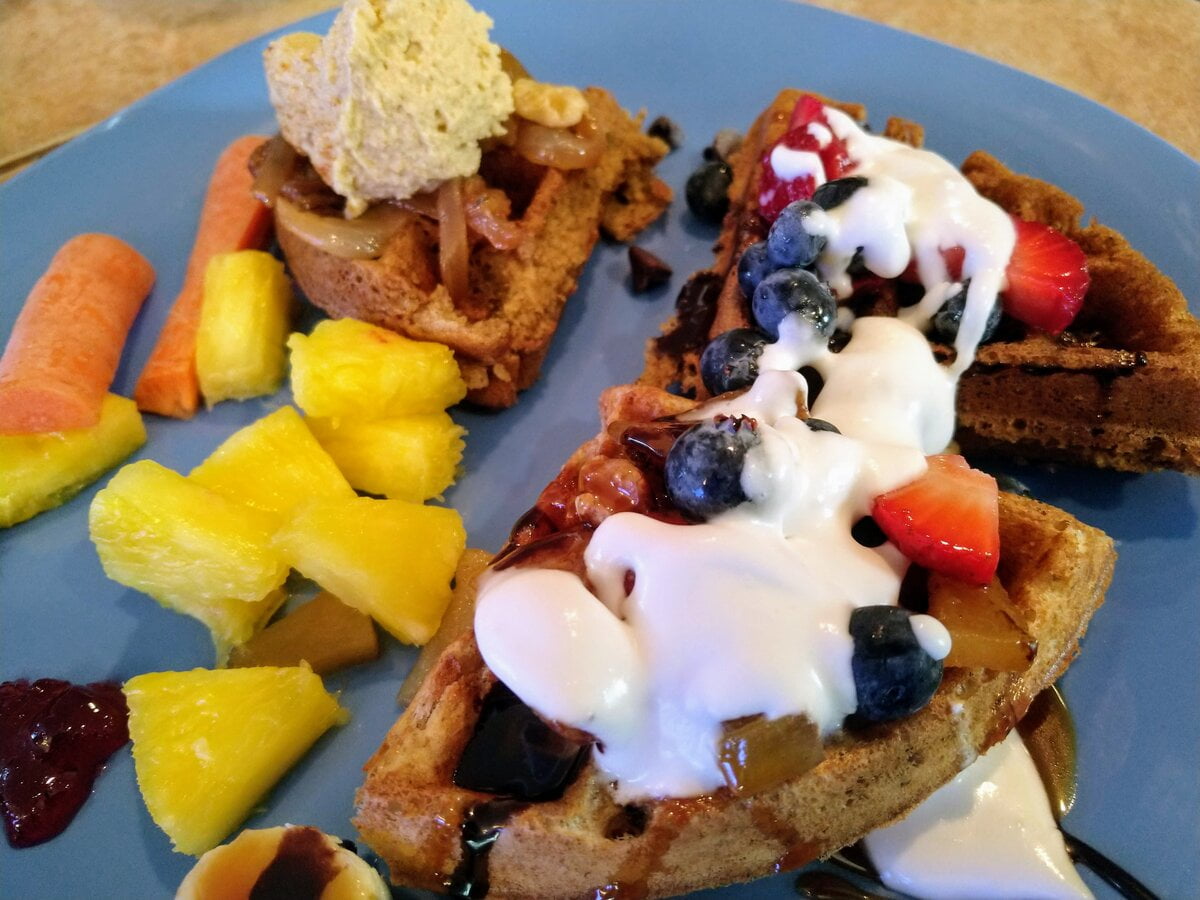 vegan waffle topped with strawberries, blueberries, coconut cream, and pineapple